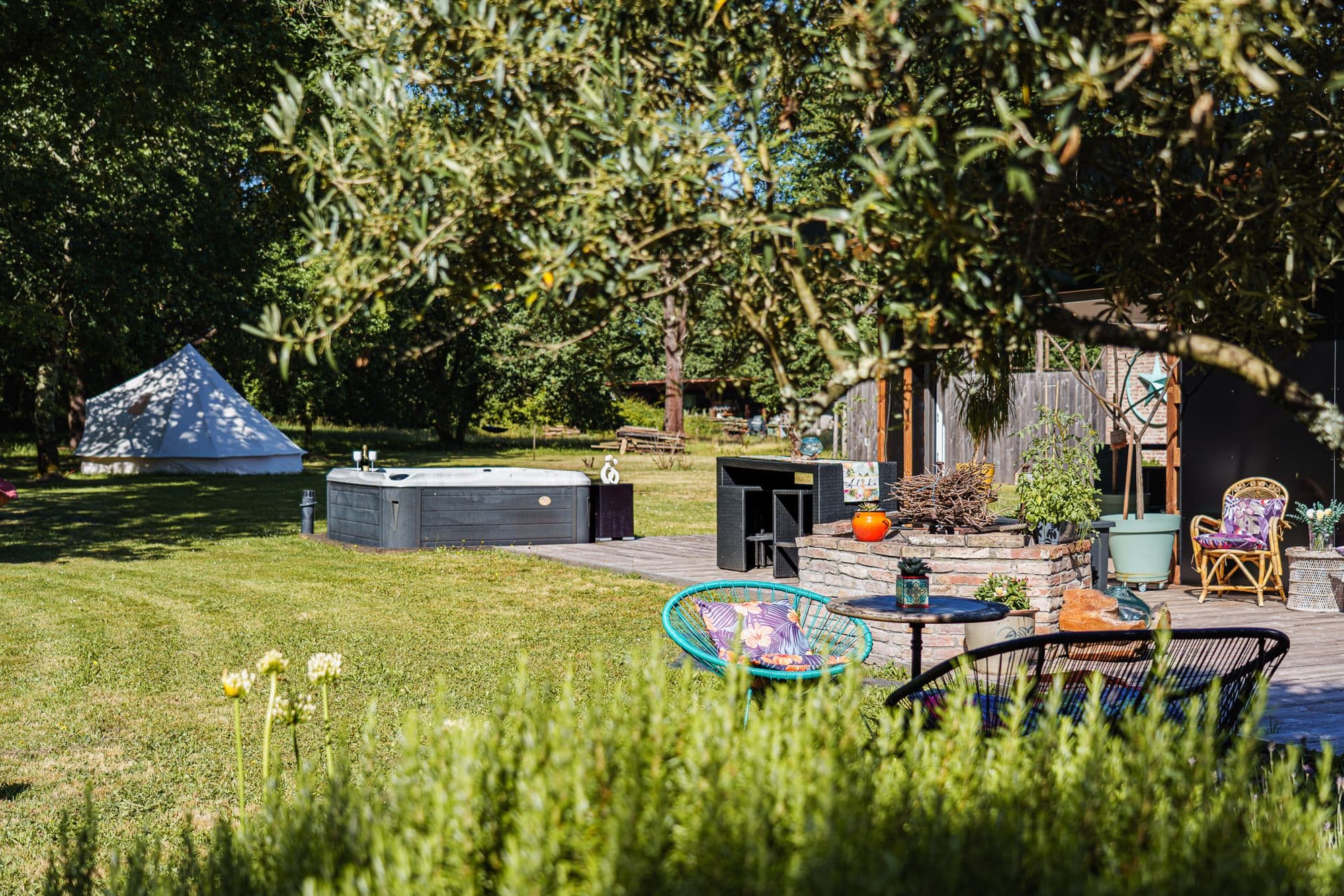 Le parc de la Chill House au Pian-Médoc : le tipi blanc, le spa et les fauteuils sous les arbres