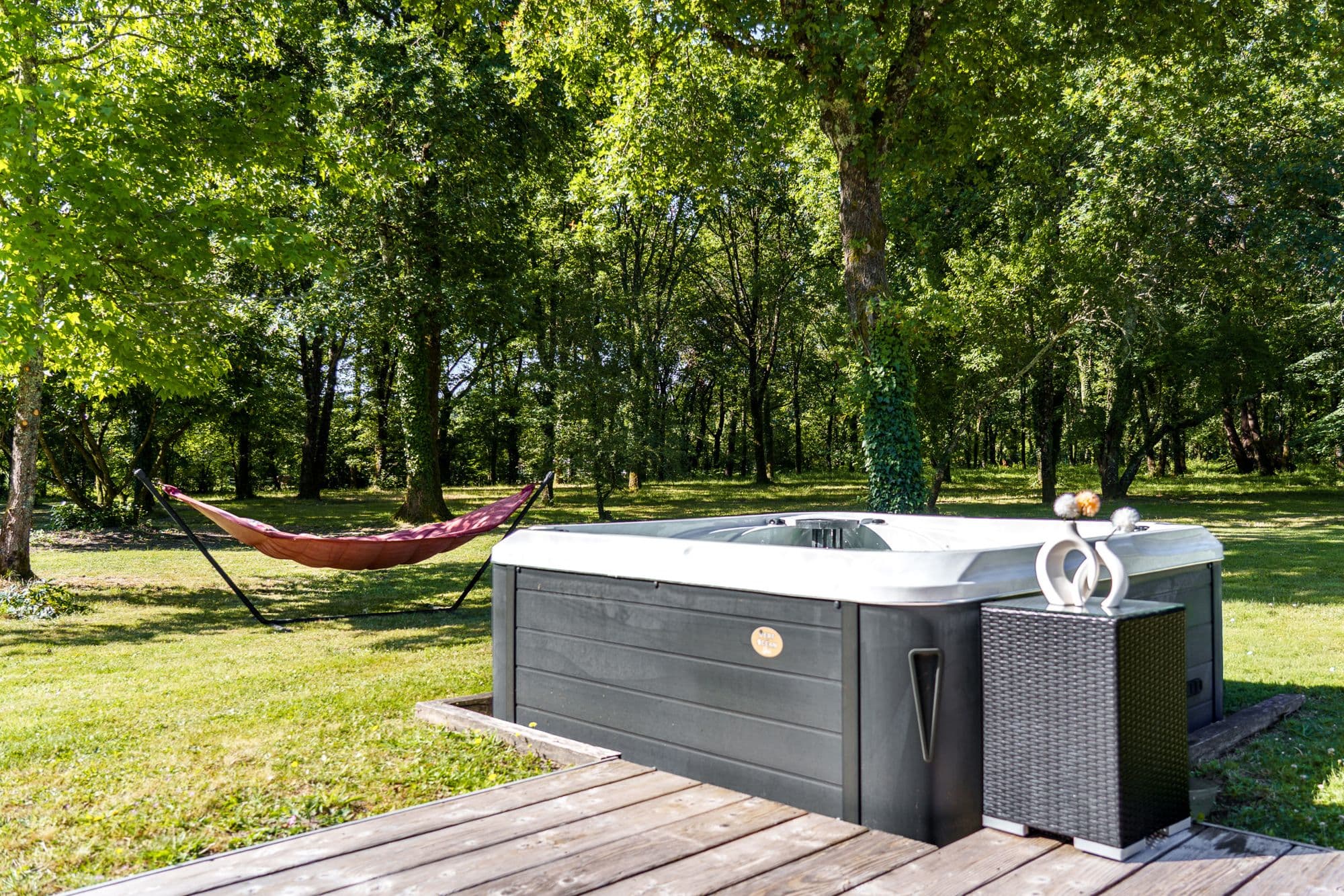 Le spa sur la terrasse en bois, le hamac tendu entre les arbres